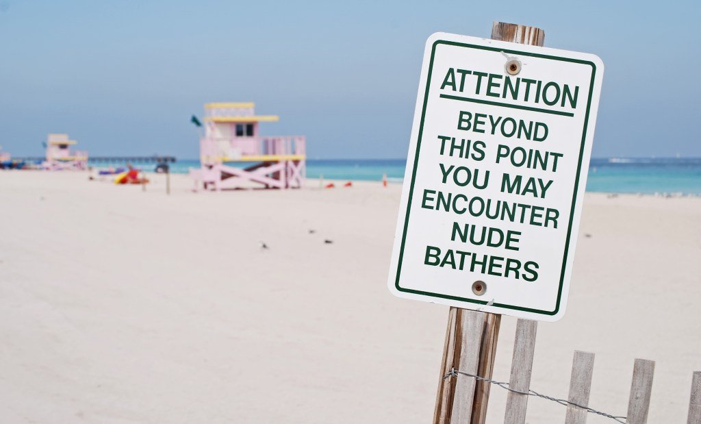 A sign that says: Attention: beyond this point you may encounter nude bathers